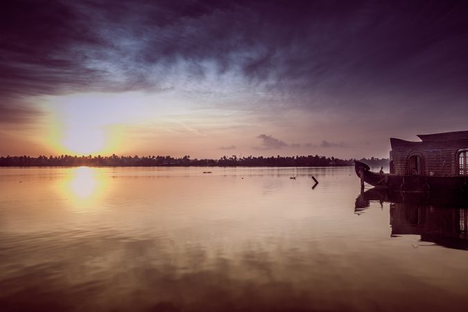 A golden sunrise over tranquil waters in Kerala casts a warm glow on the serene landscape, promising a day of peaceful bliss - euppy